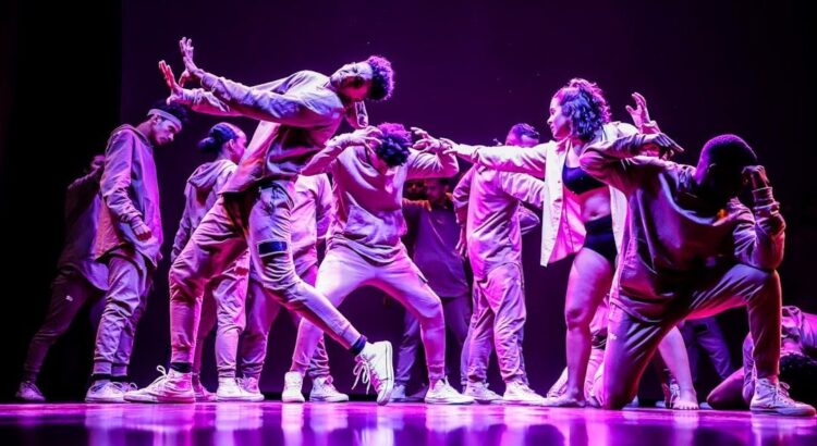 Dansers vormen een expressieve groep op een paars verlicht podium