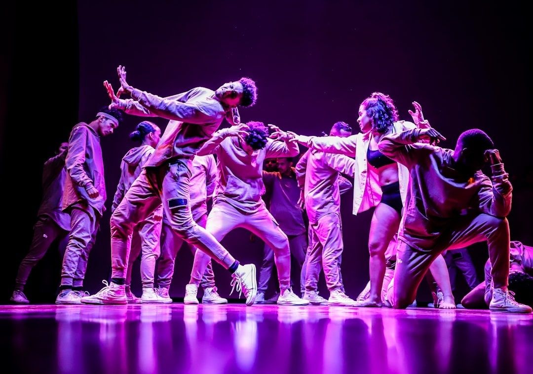Dansers vormen een expressieve groep op een paars verlicht podium