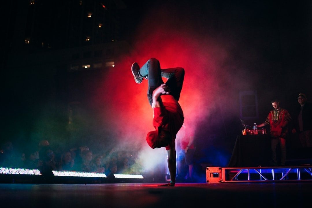 Streetdancer voert een gestileerde freeze uit in rood podiumlicht