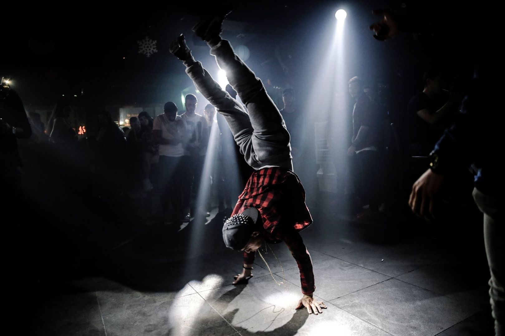 Breakdancer voert een handstand uit in een donkere danscirkel
