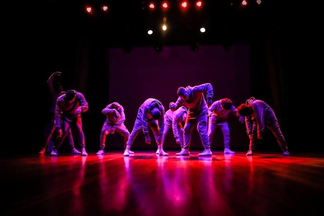 Dansers voeren synchroon een locking- of poppingchoreografie uit op een verlicht podium